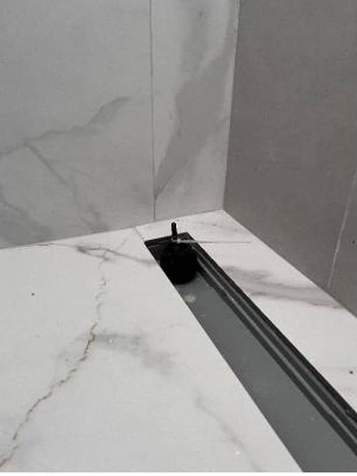 Banheiro com ralo tamponado e lâmina d'água sobre o piso durante ensaio de resistência à umidade